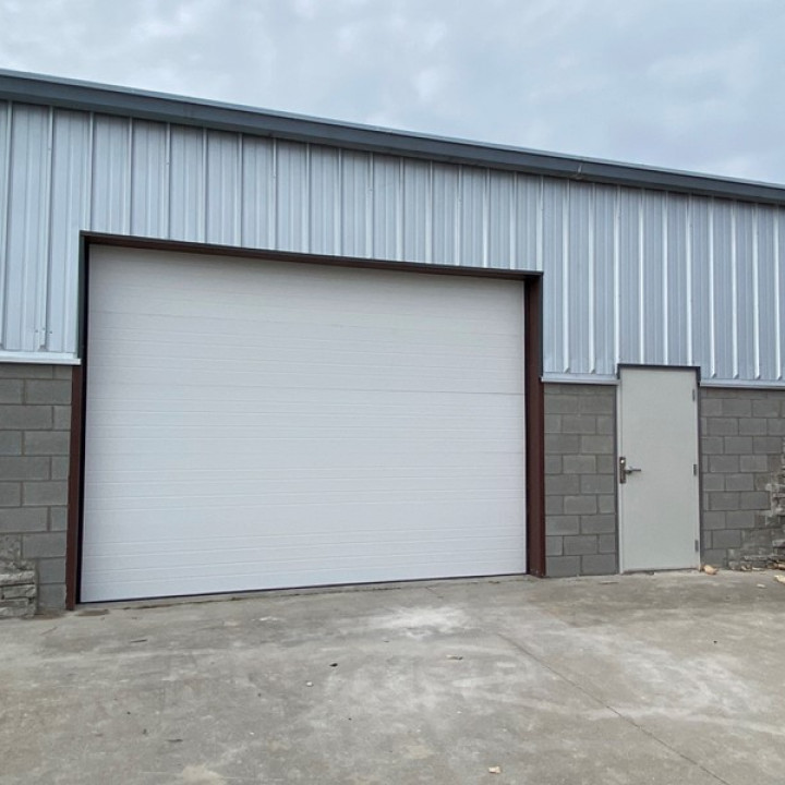 Commercial warehouse exterior with large garage door after restoration and repair services