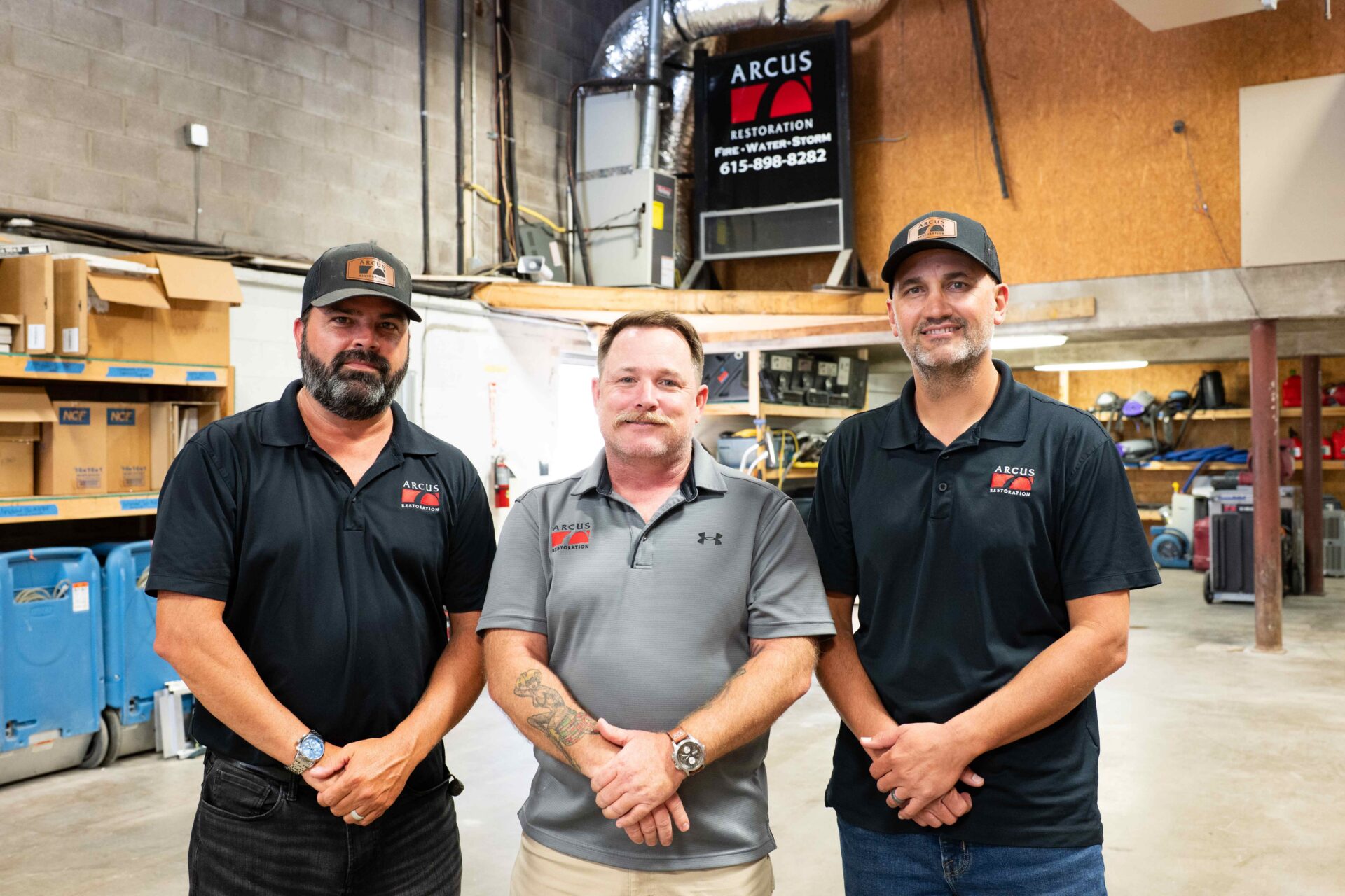 Three members of the Arcus Restoration team standing in the company warehouse