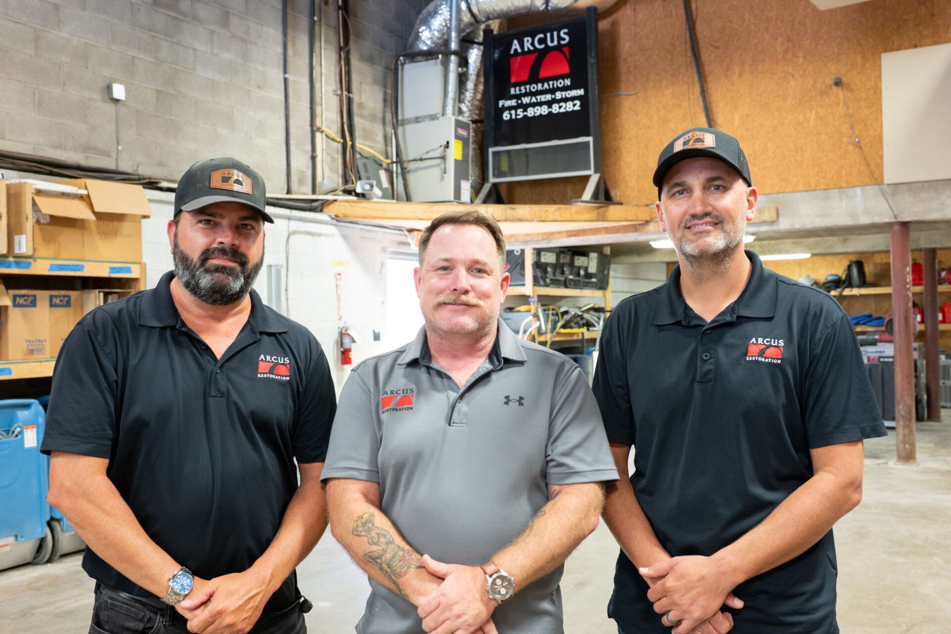 Three members of the Arcus Restoration team standing in the company warehouse