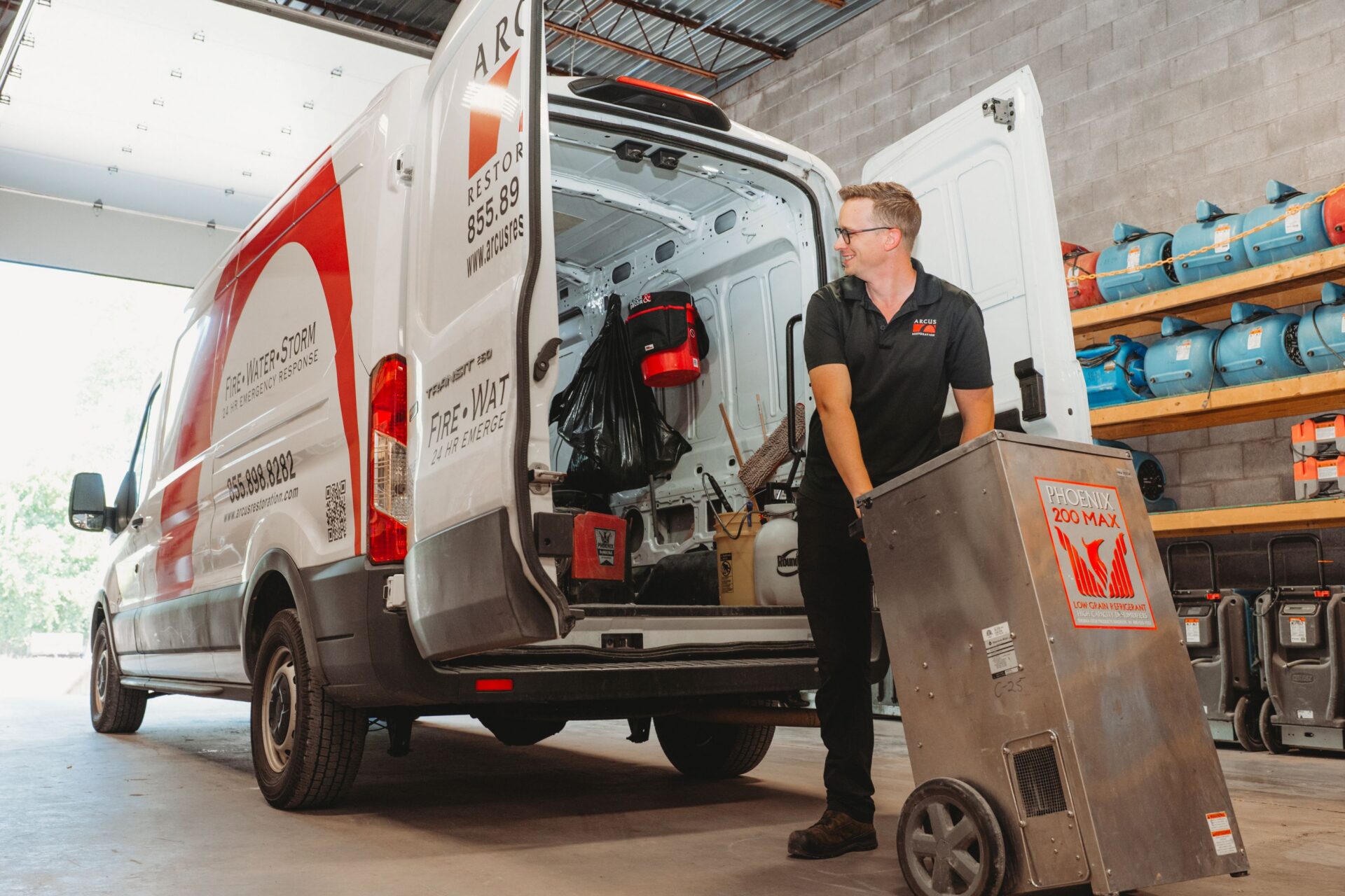 Arcus Restoration technician loading restoration equipment into a service van