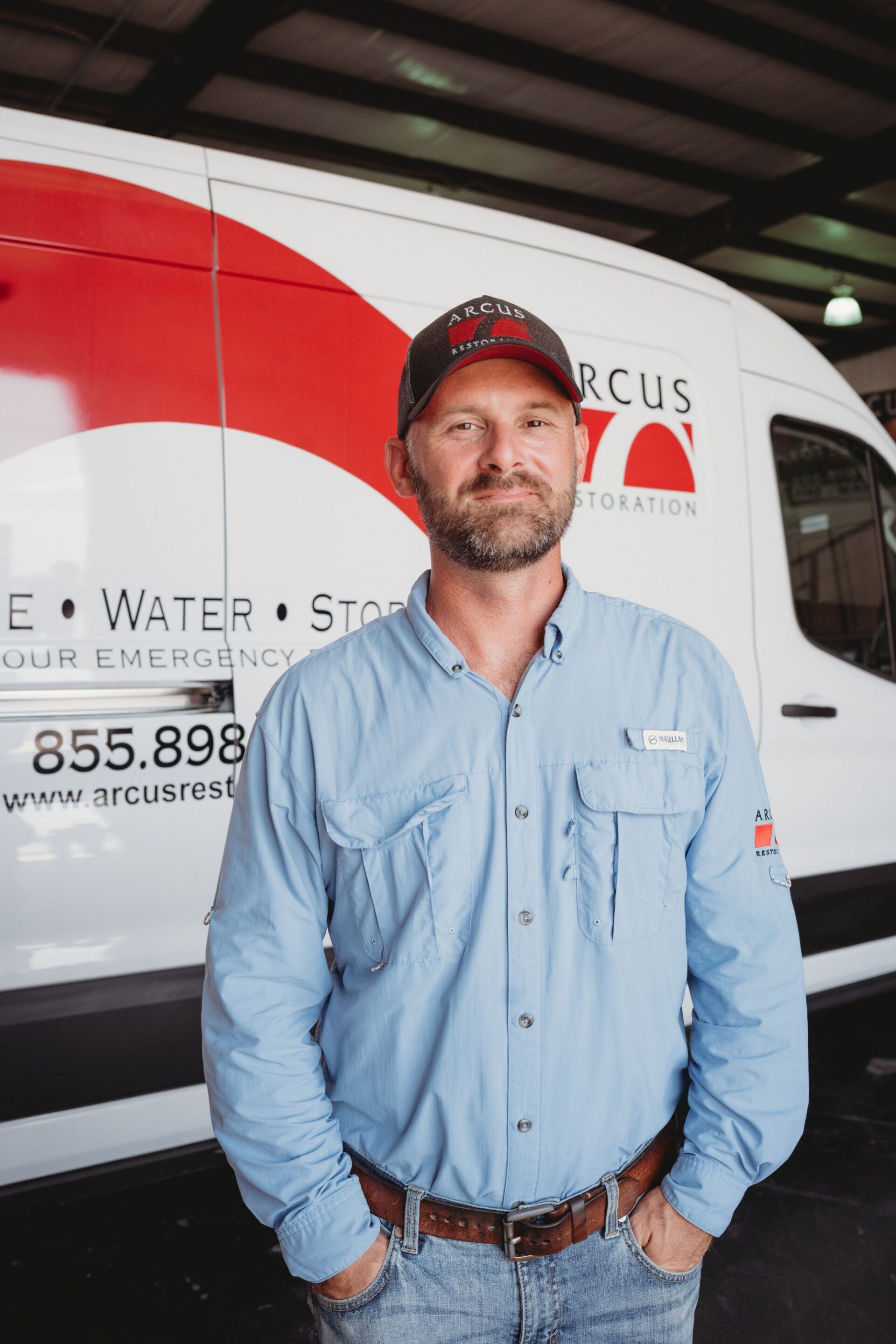 Arcus Restoration team member standing in front of a company service van