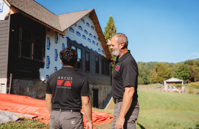 Arcus Restoration project manager talking with a homeowner outside a house under repair