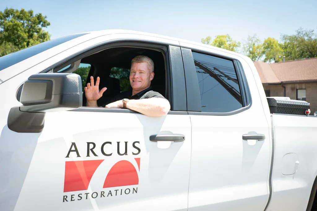 Arcus Restoration team member waving from a company pickup truck